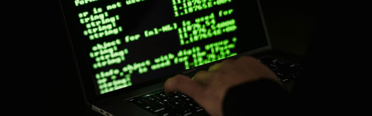 Banner photo of an alleged criminal working at a computer.